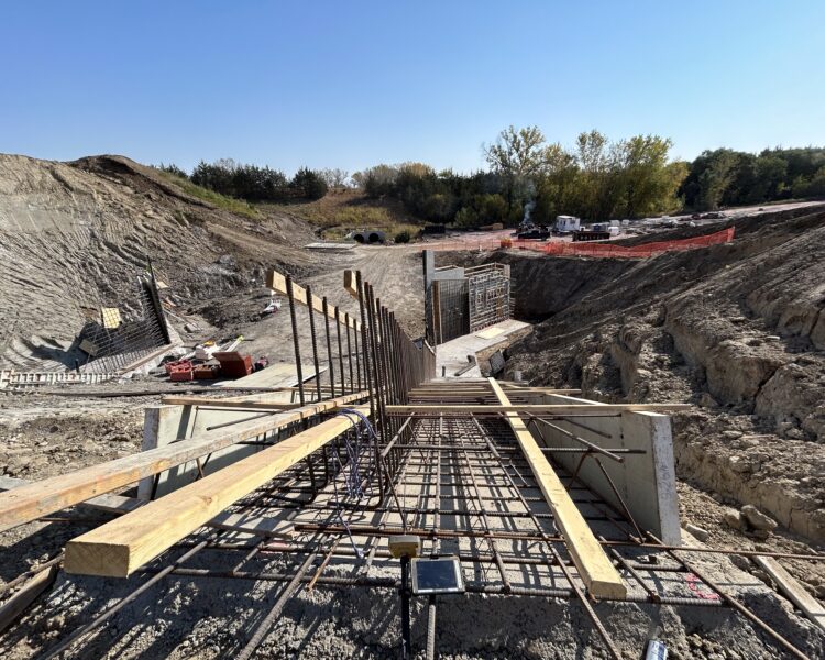 Construction site: rebar, wood, concrete forms under clear sky.