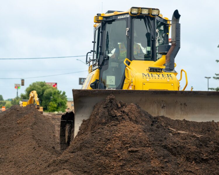 Yellow Meyer bulldozer pushes dirt; other machines in background.